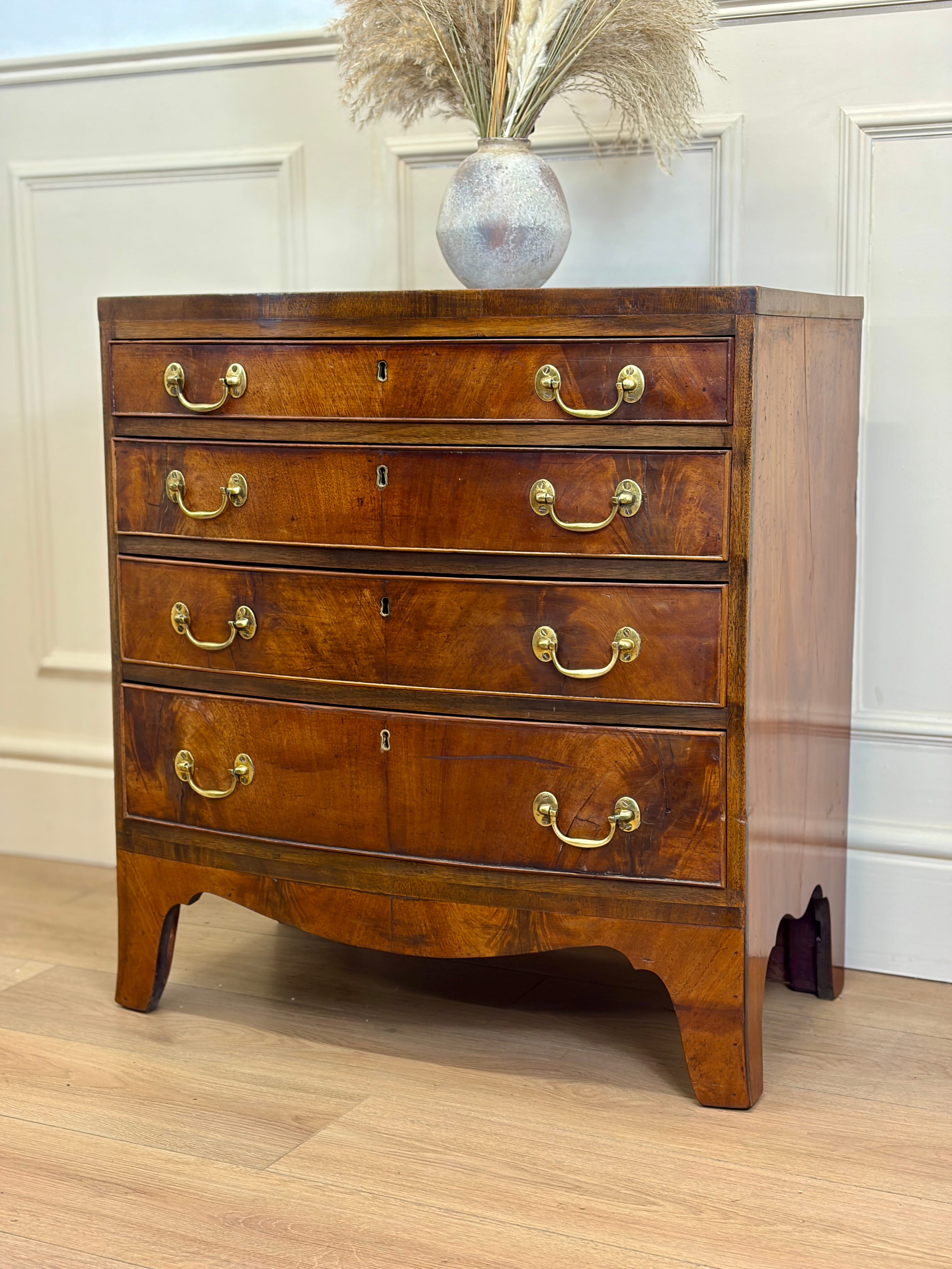 Wooden dresser with gold handles against a white paneled wall.