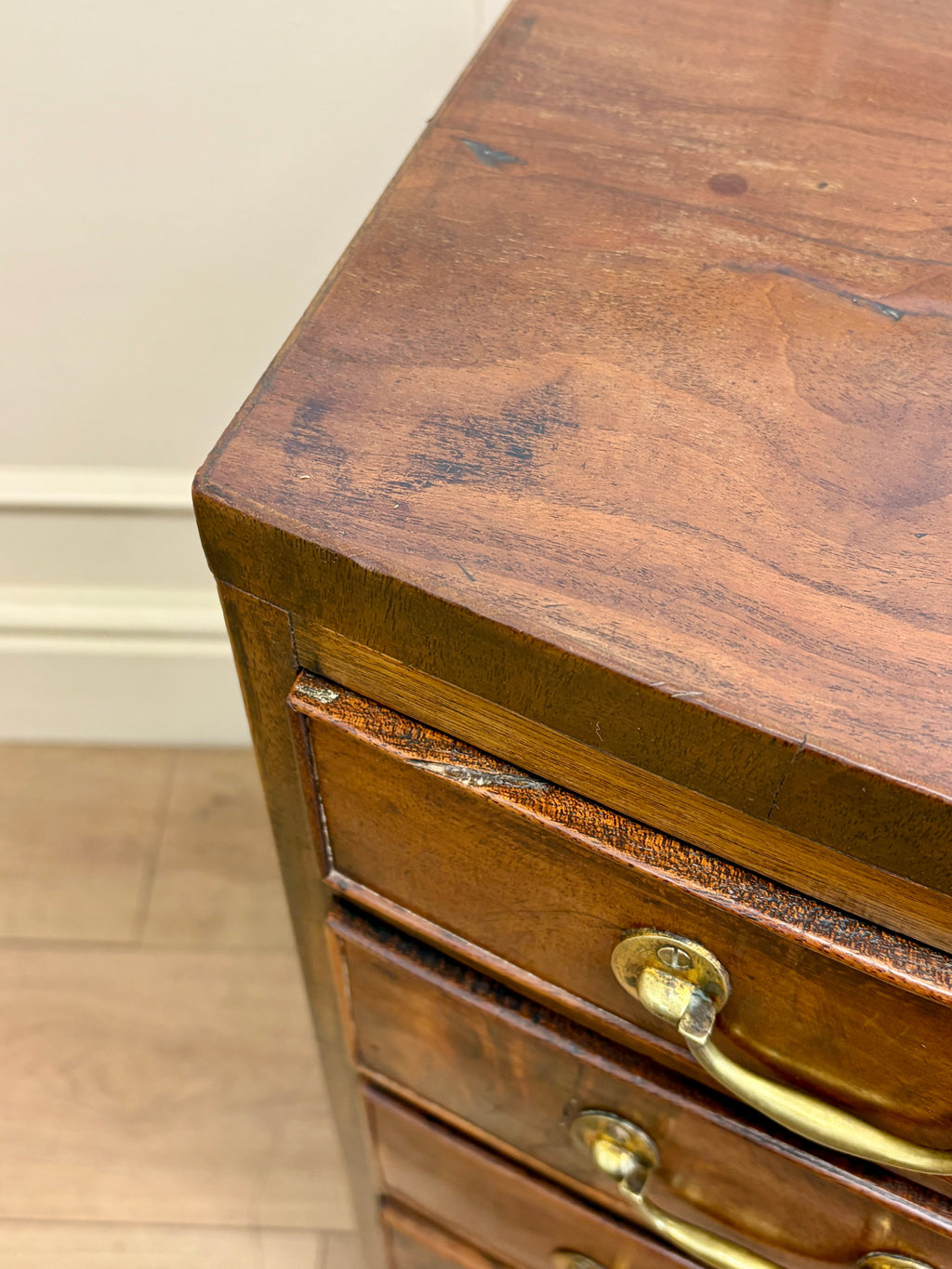 Wooden drawer with brass handles on a wooden floor.