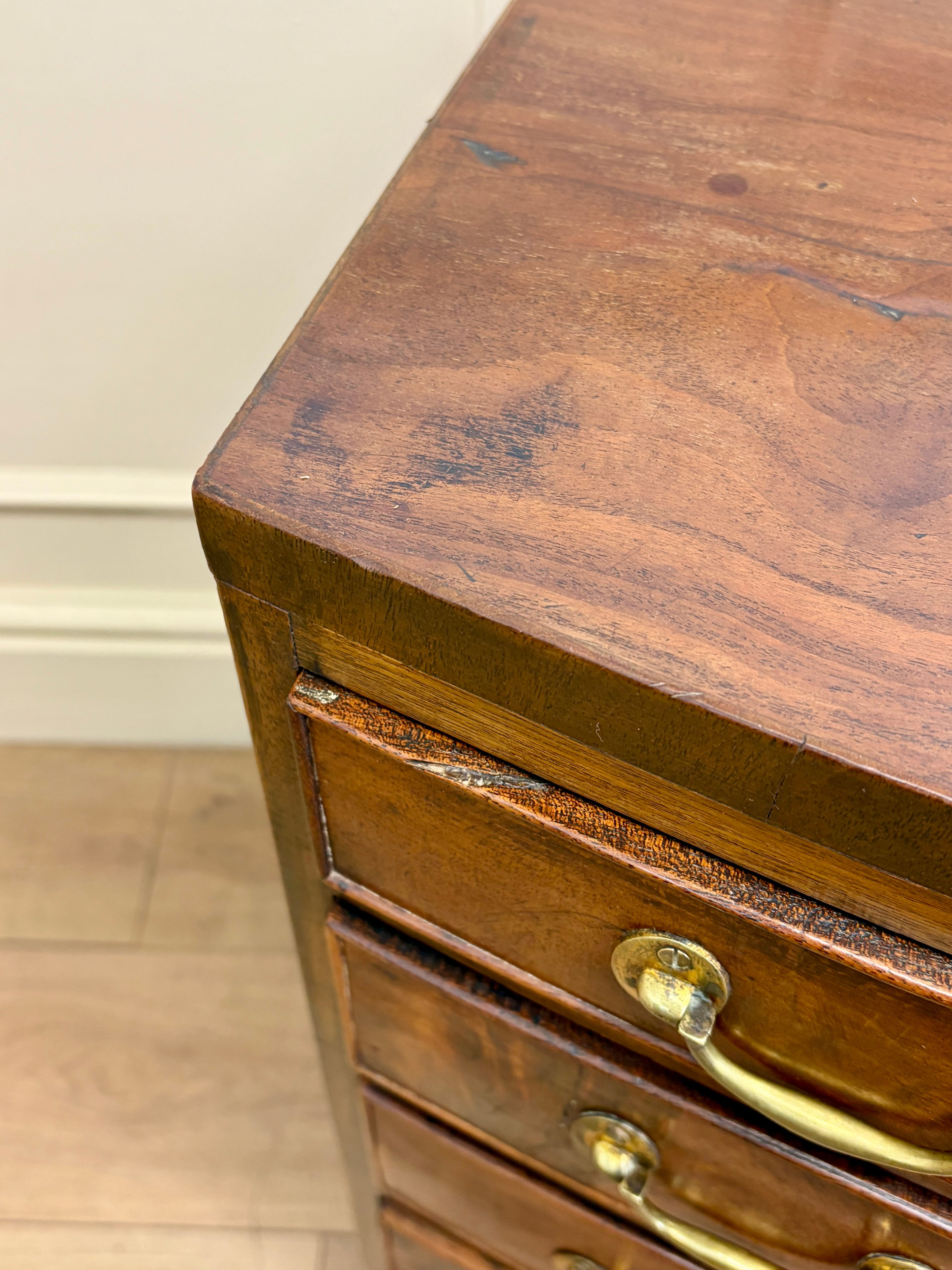 Wooden drawer with brass handles on a wooden floor.