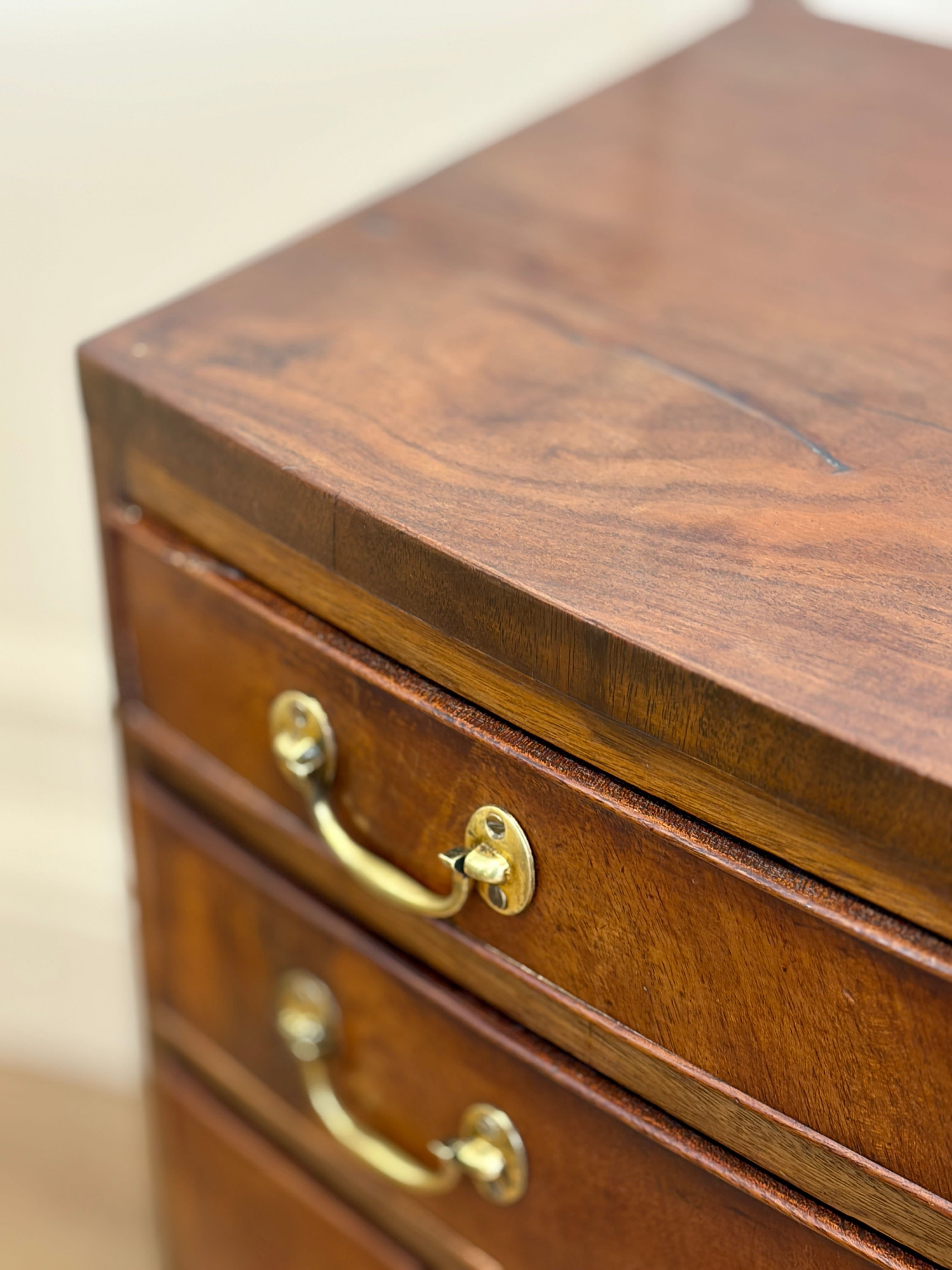 Wooden chest of drawers with brass handles on a plain background