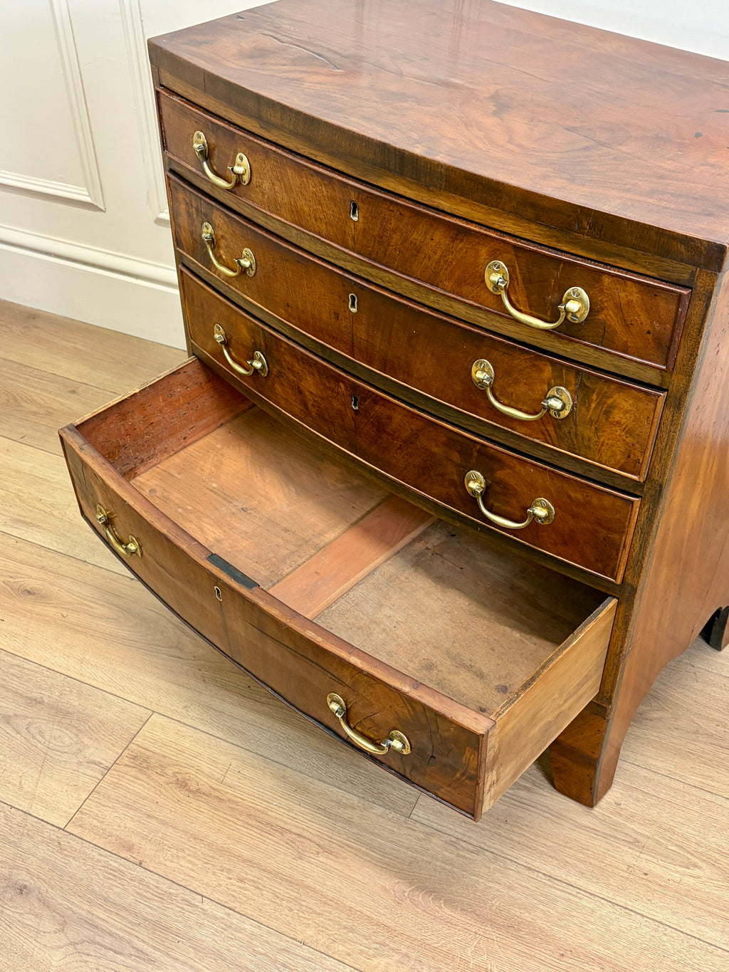 Wooden dresser with open drawer on a wooden floor