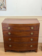 Wooden dresser with brass handles on a wooden floor.