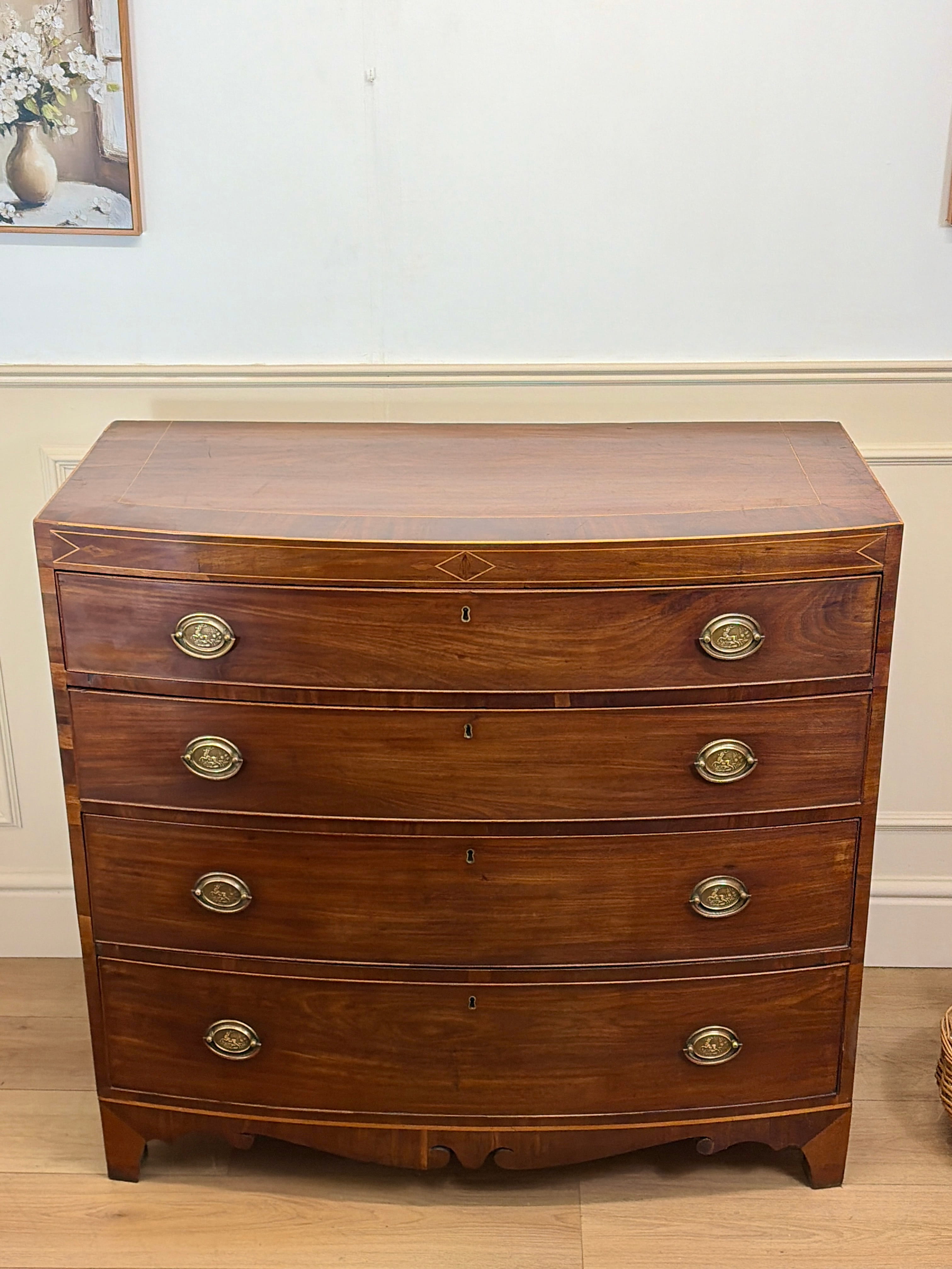 Wooden dresser with brass handles on a wooden floor.