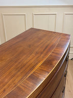 Wooden dresser with a smooth, polished surface against a neutral wall.