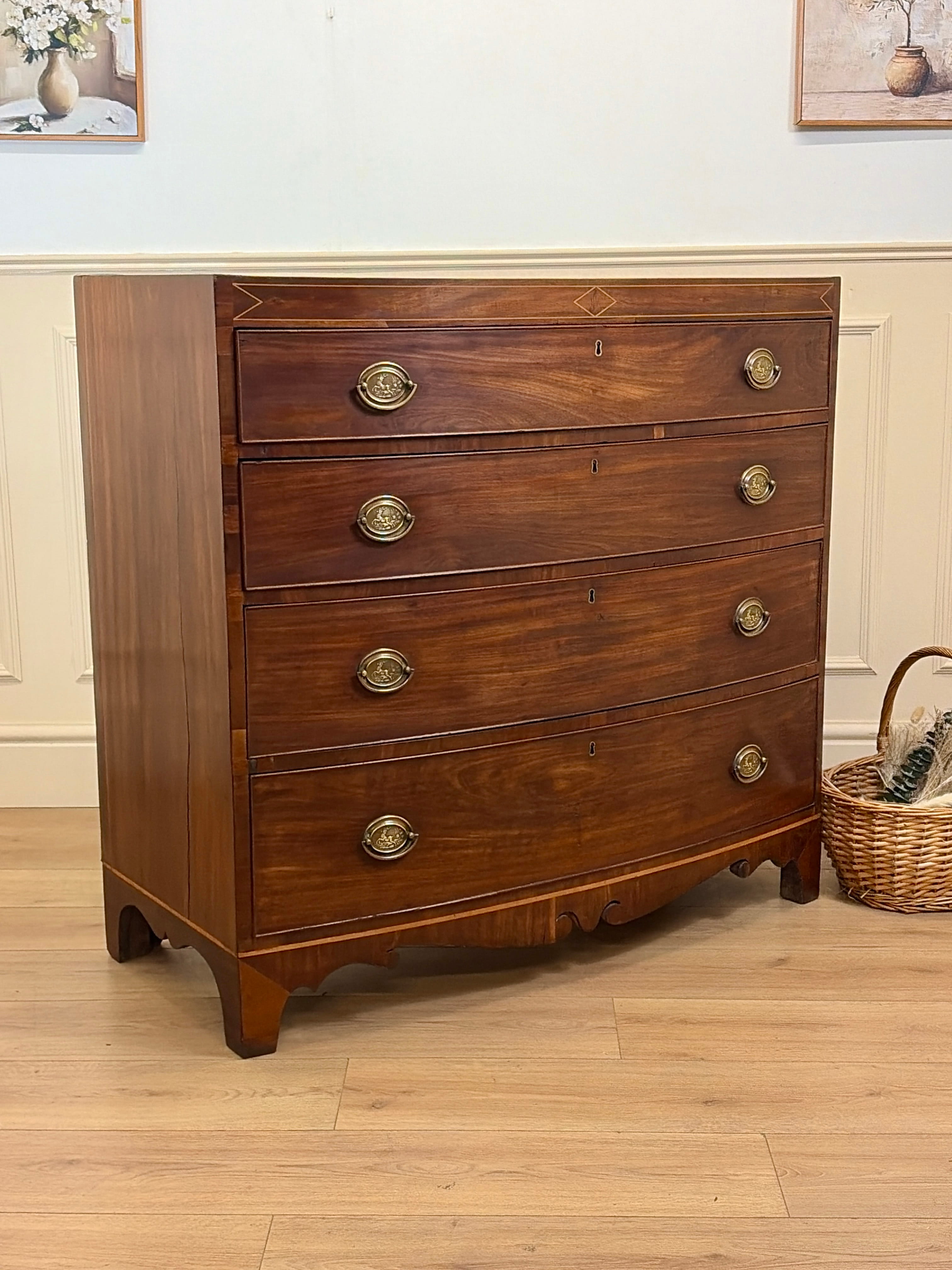 Wooden dresser with brass handles in a room with a light blue wall and wooden floor.