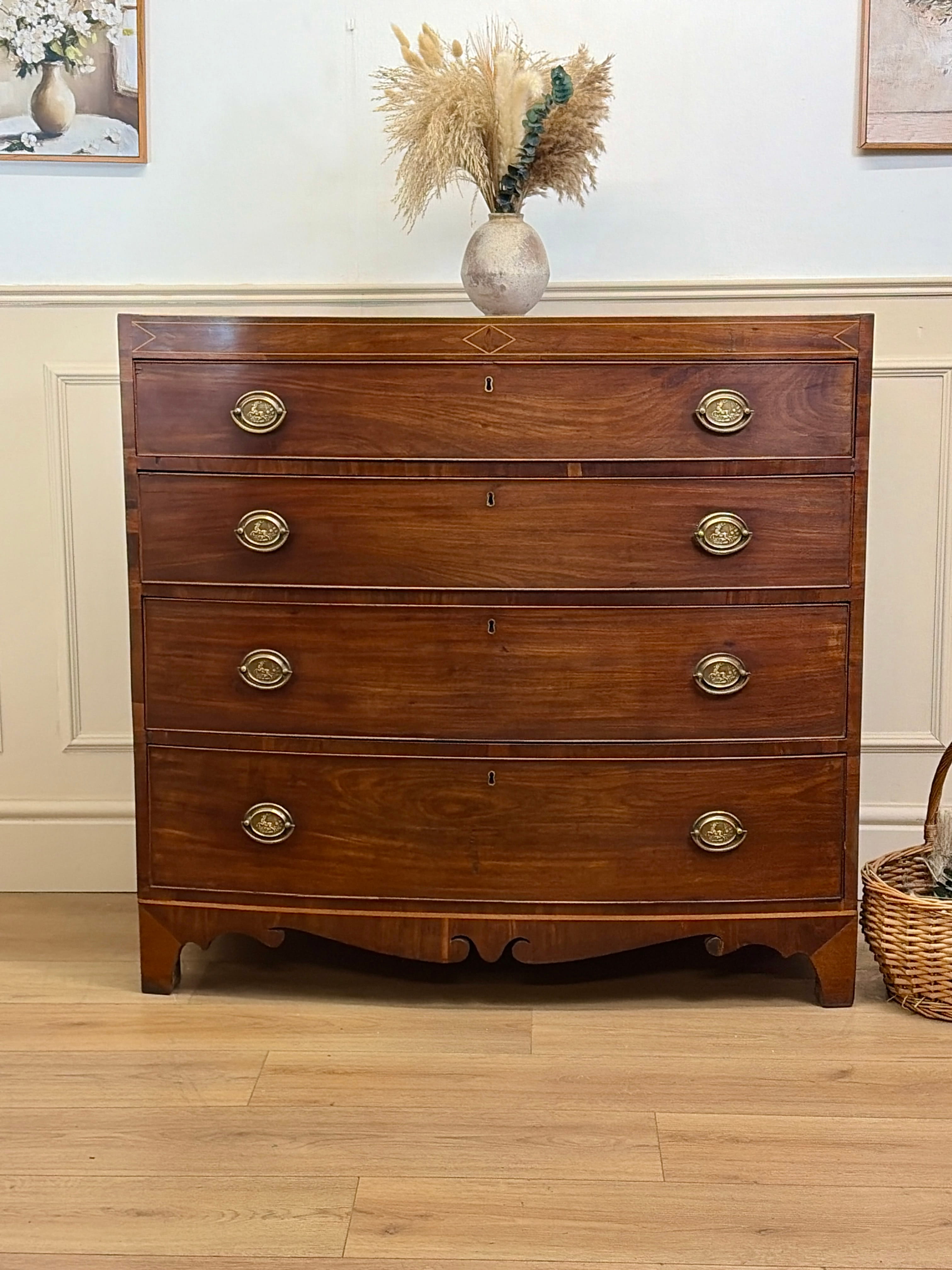 Wooden dresser with brass handles in a room with a vase of flowers on top