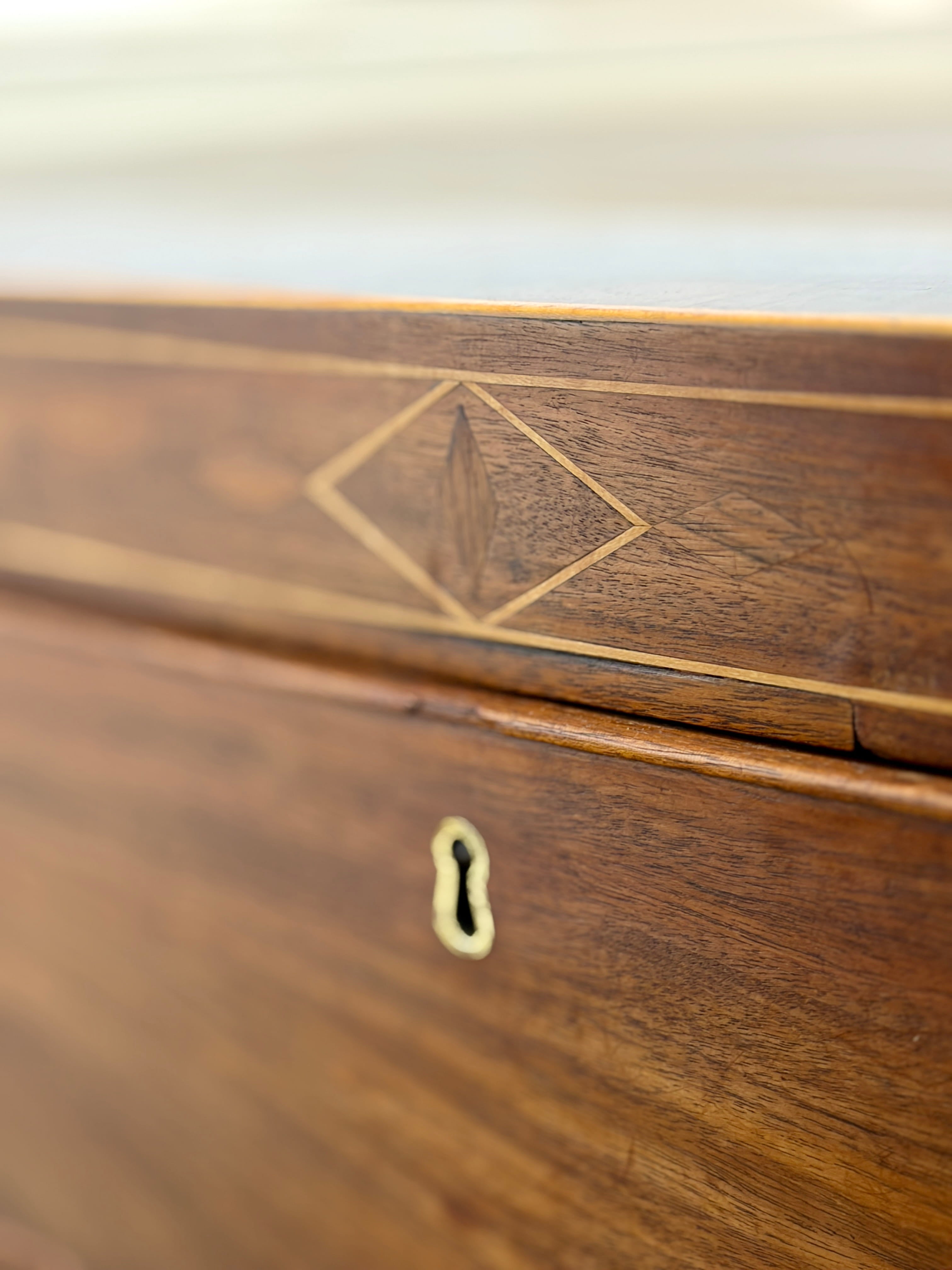 Close-up of a wooden drawer with intricate inlay work and keyhole.