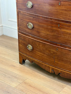 Wooden dresser with brass handles on a wooden floor.