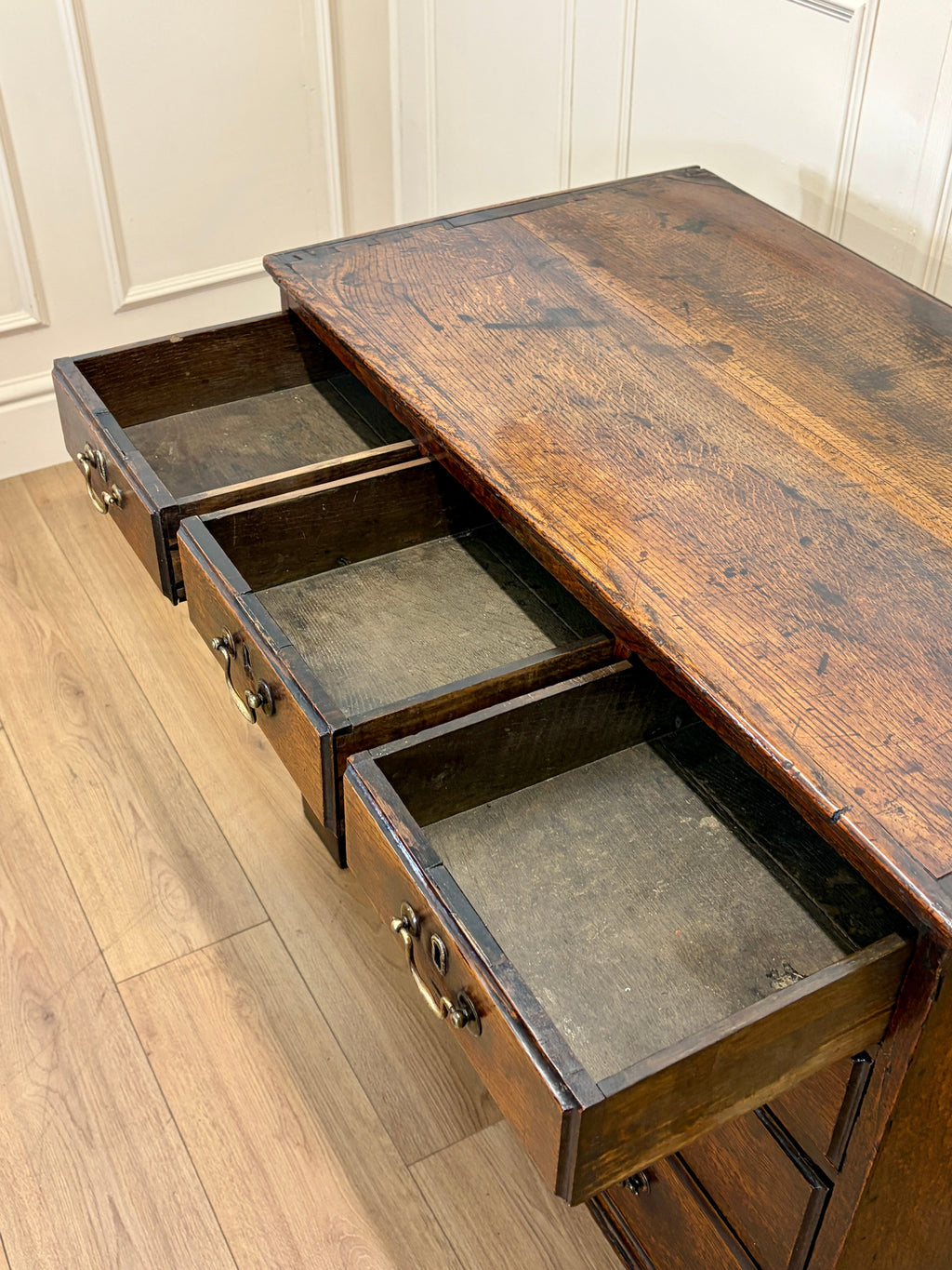Wooden desk with three drawers on a wooden floor.