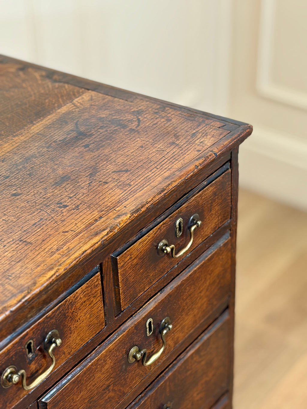 Close-up of an old wooden dresser with brass handles on a neutral background