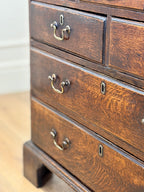 Close-up of a wooden dresser with drawers and brass handles.