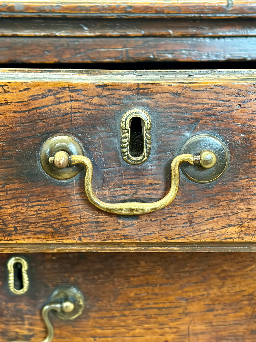 Close-up of a wooden drawer with brass handles and keyhole.