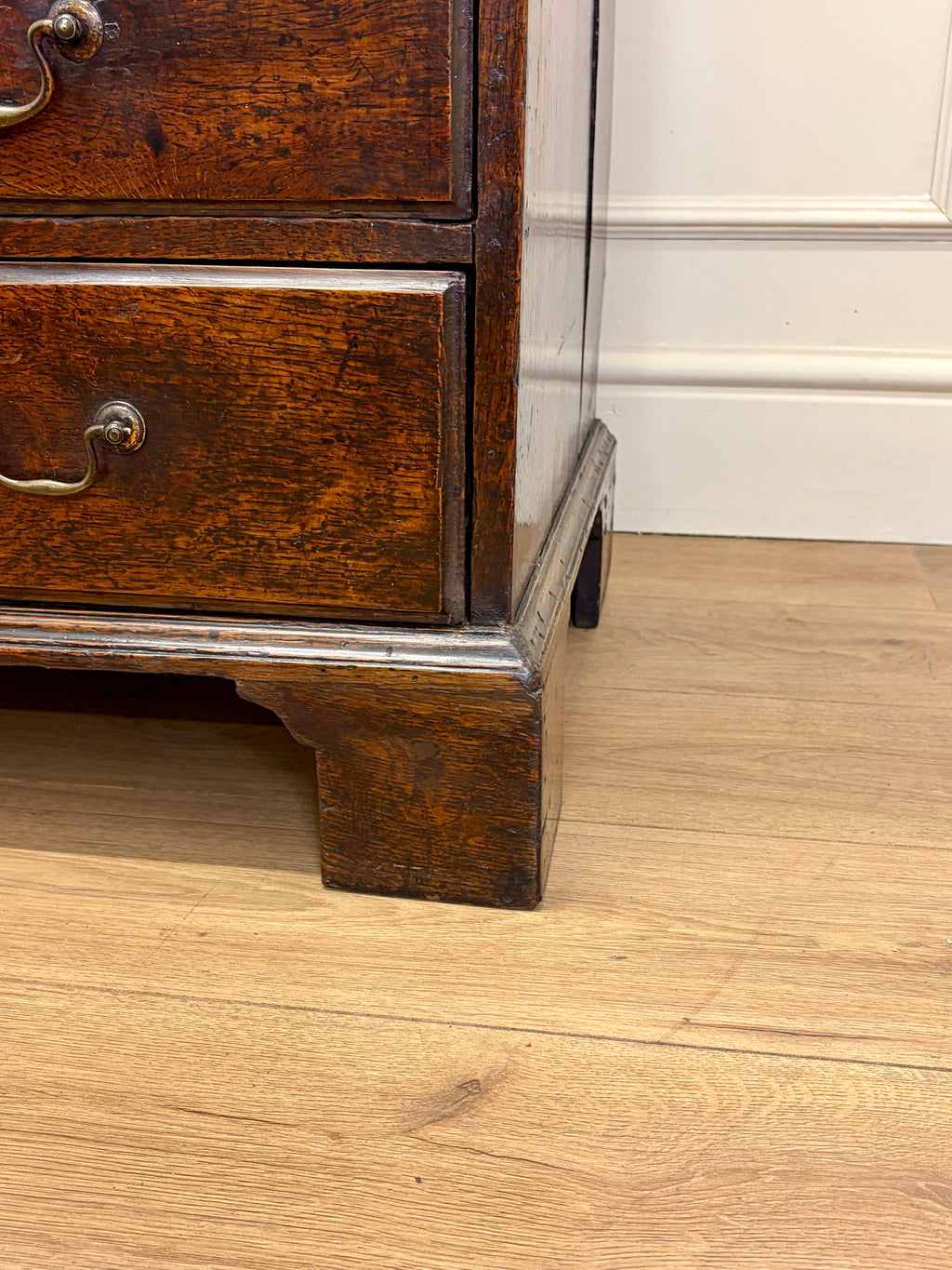 Wooden drawer unit on a wooden floor with a white wall in the background