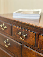 Close-up of a wooden dresser with brass handles on a neutral background