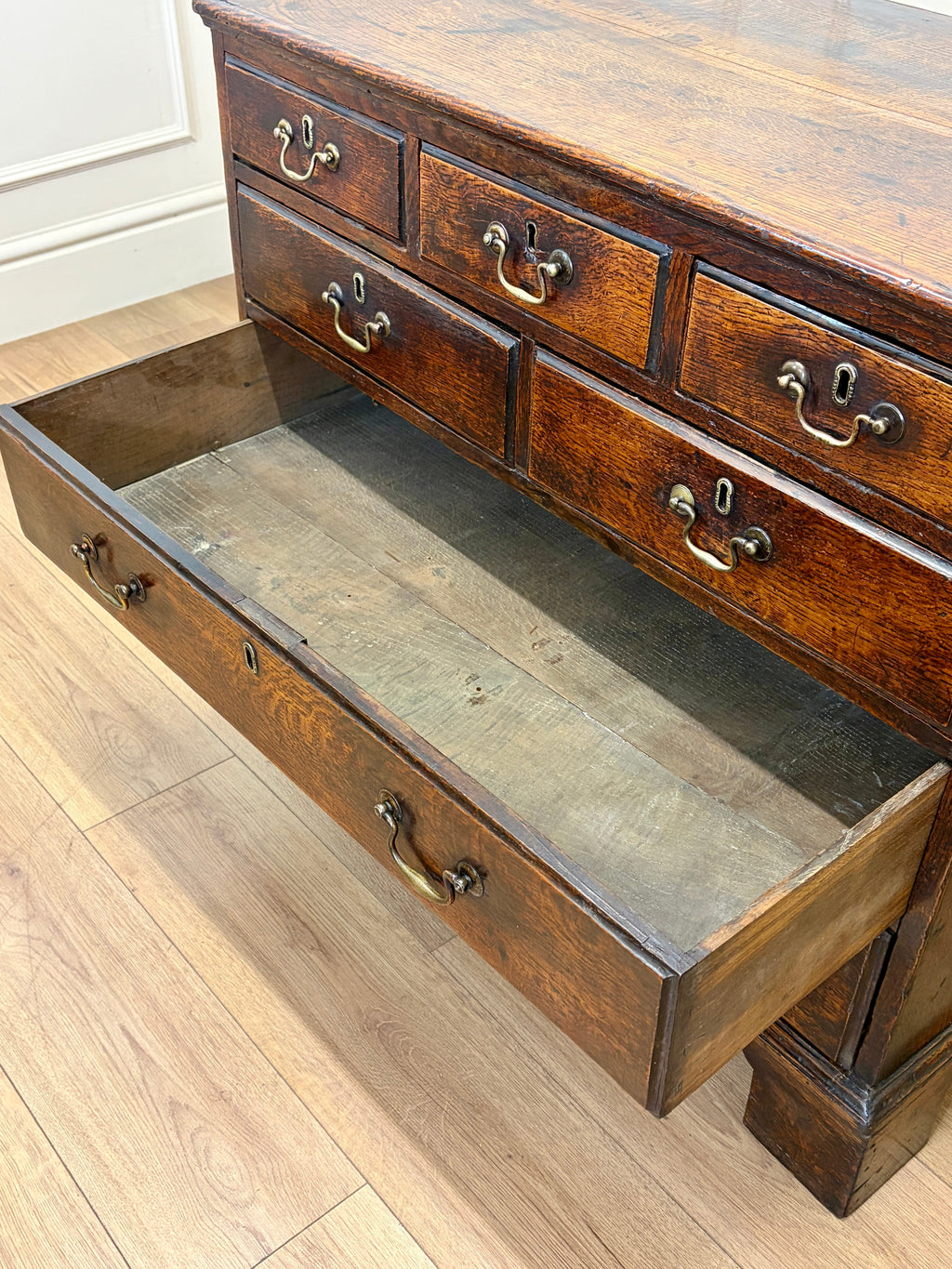 Wooden dresser with open drawer on a wooden floor