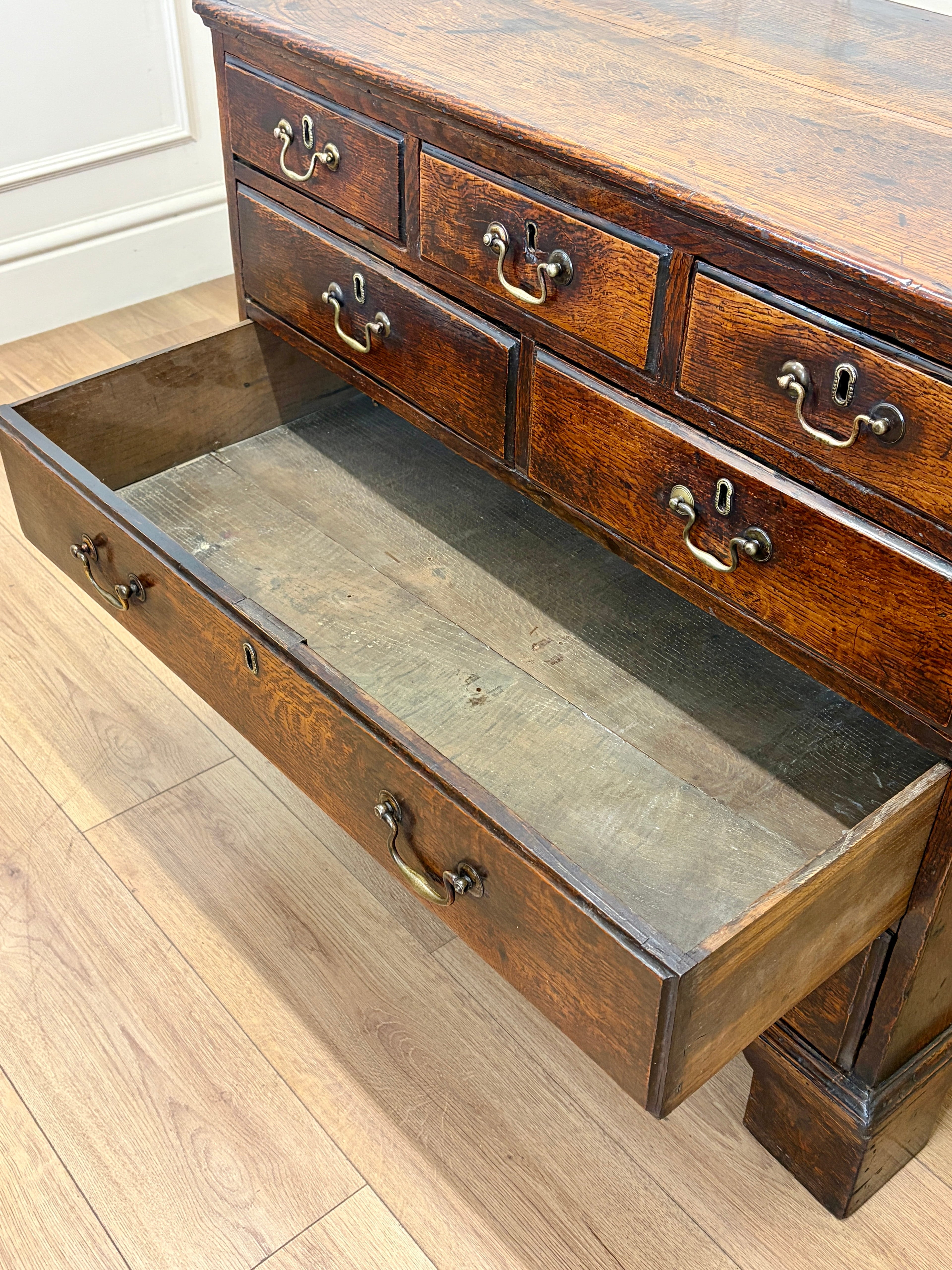 Wooden dresser with open drawer on a wooden floor