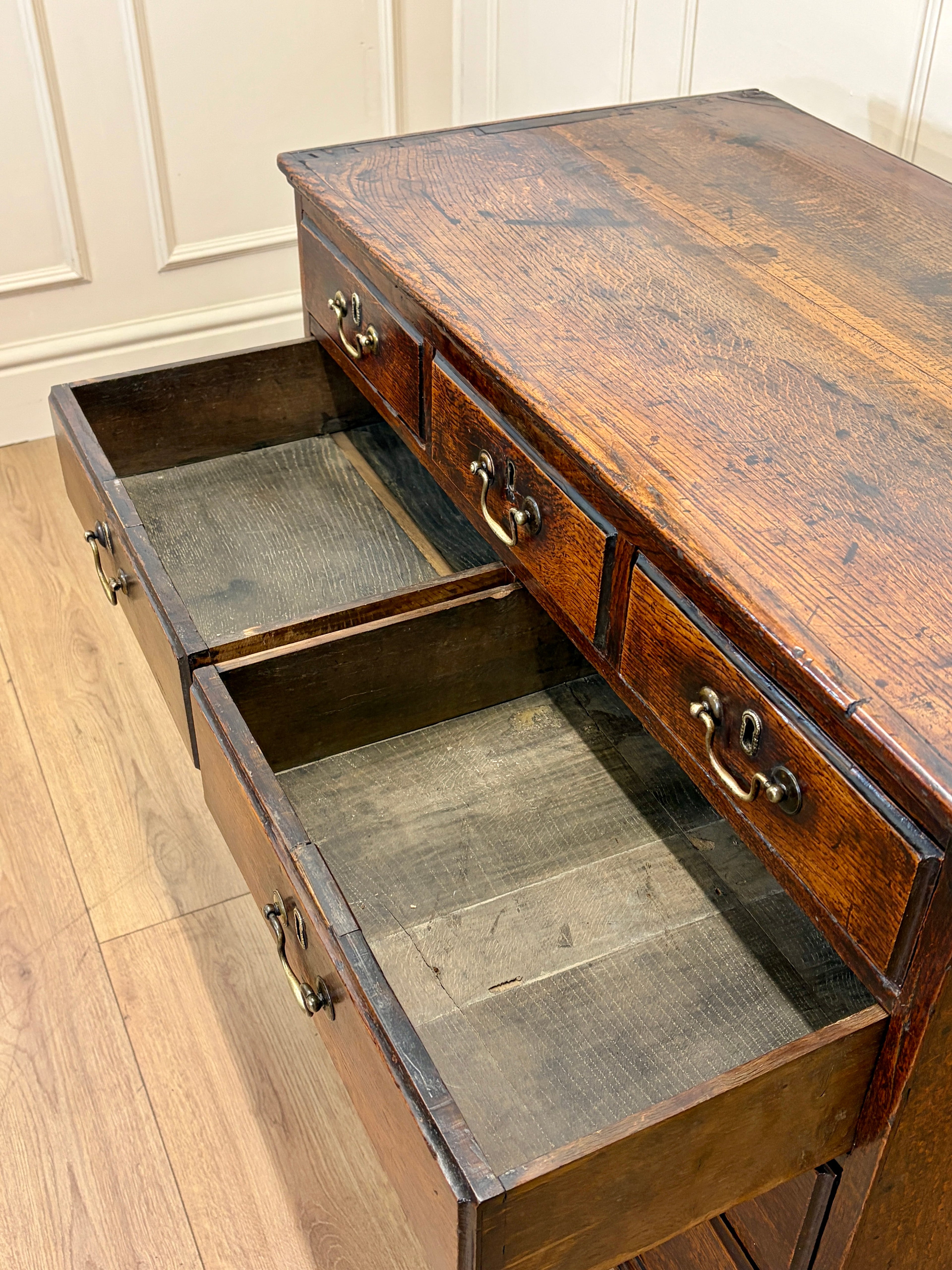 Wooden desk with open drawers on a wooden floor.