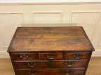 Vintage wooden desk with multiple drawers against a white paneled wall.