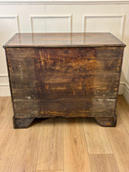 Vintage wooden dresser with a glass top on a wooden floor.