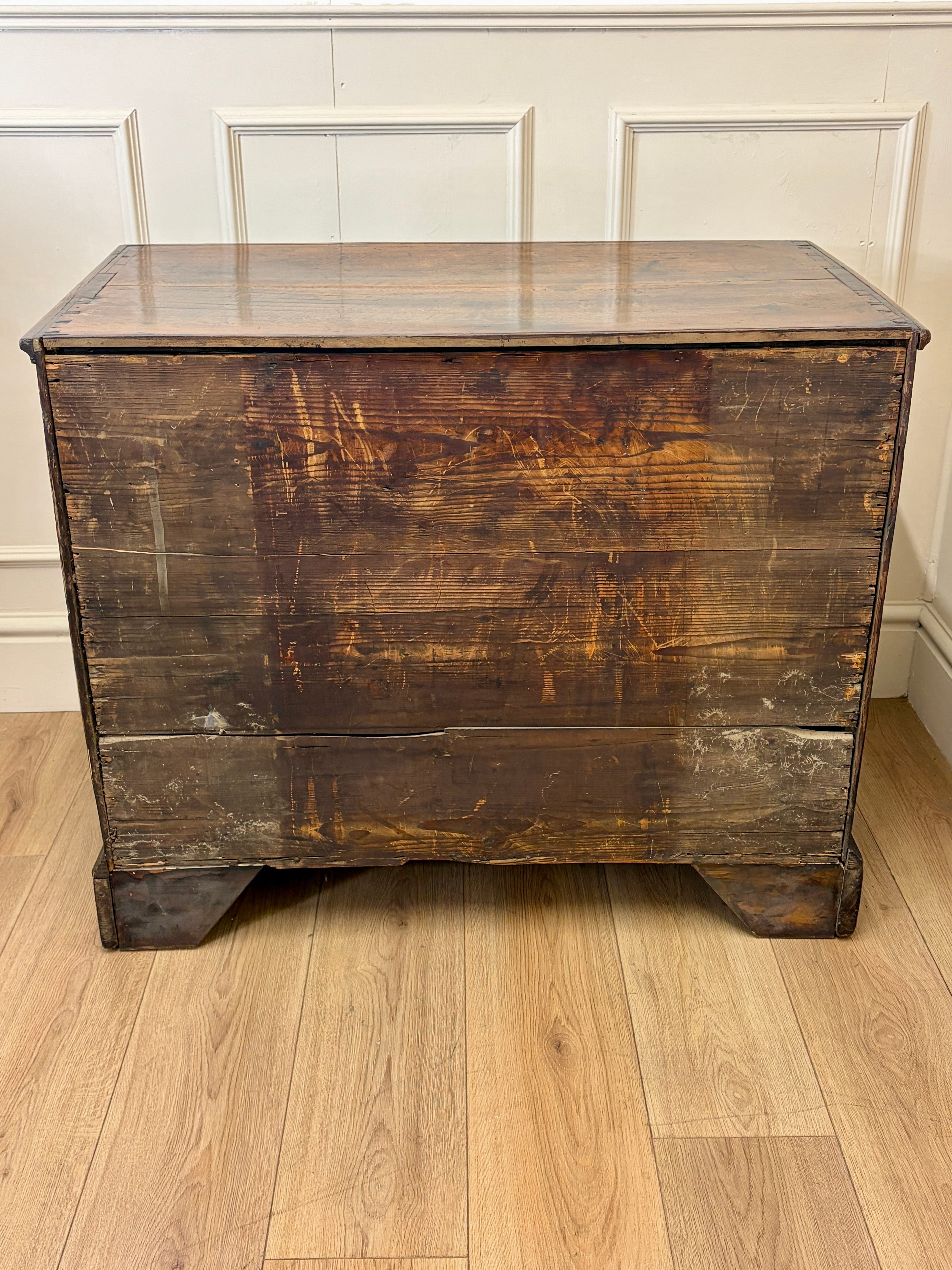 Vintage wooden dresser with a glass top on a wooden floor.