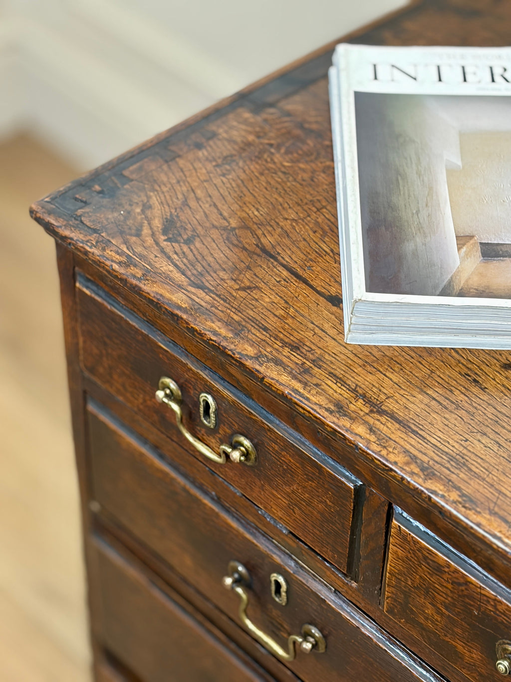 Wooden dresser with brass handles and a magazine on top