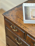 Wooden dresser with brass handles and a magazine on top