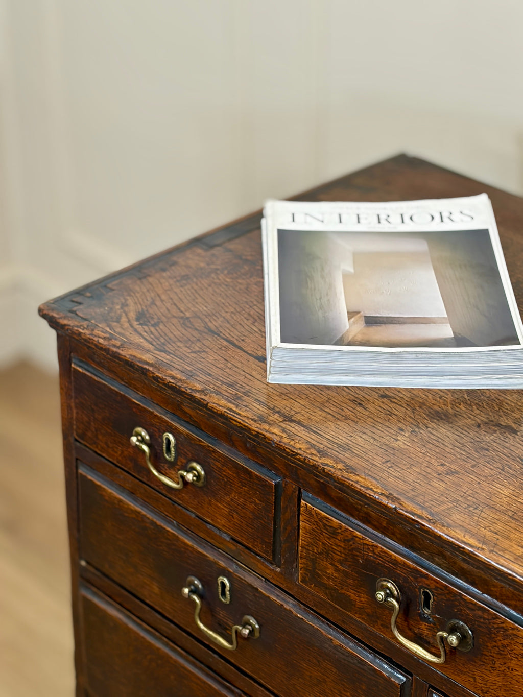 Wooden dresser with a magazine on top against a neutral background