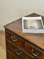 Wooden dresser with a magazine on top against a neutral background