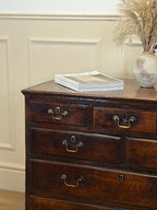 Wooden dresser with brass handles against a beige wall