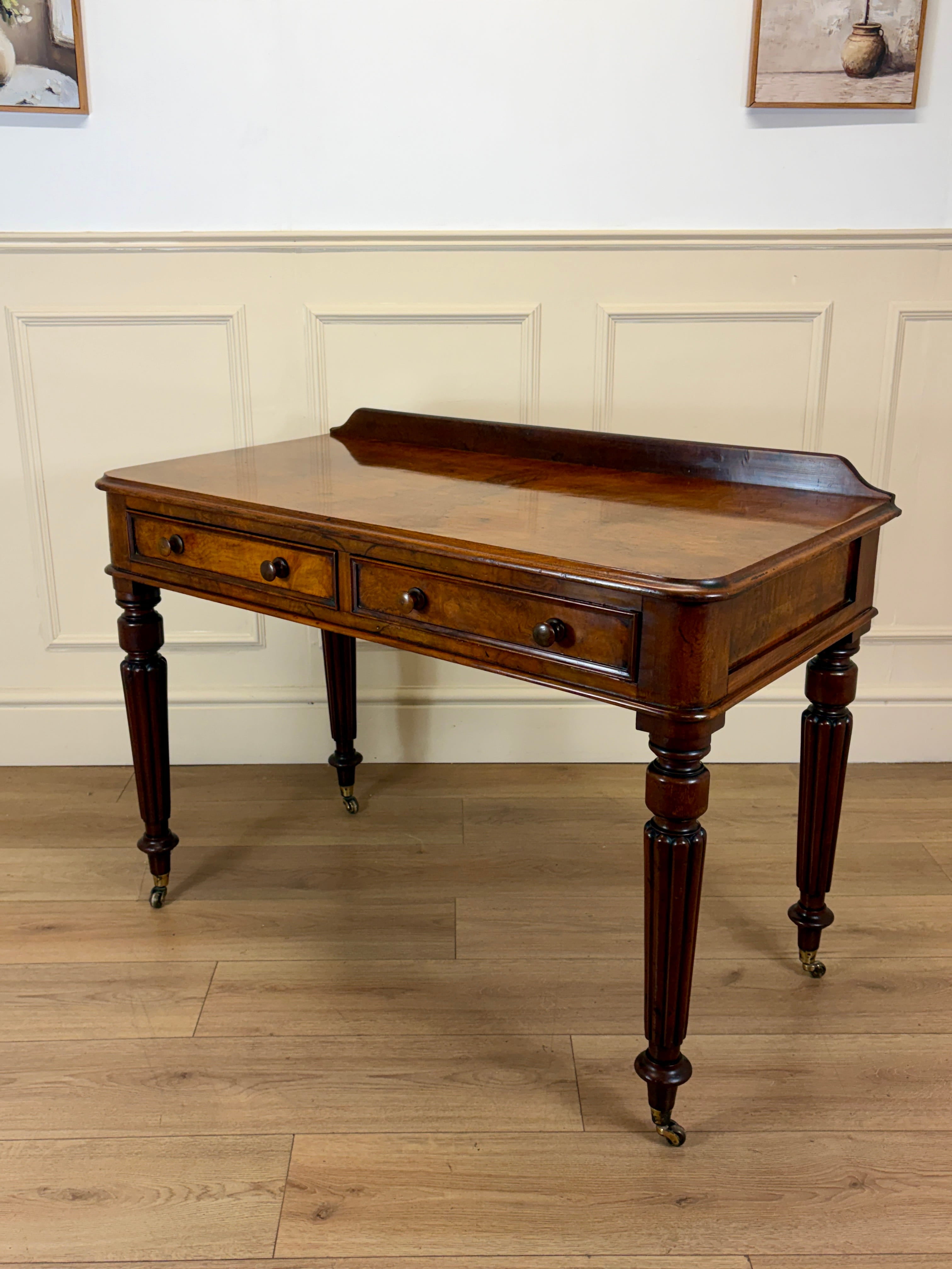 Wooden desk with drawers on a wooden floor against a white paneled wall.