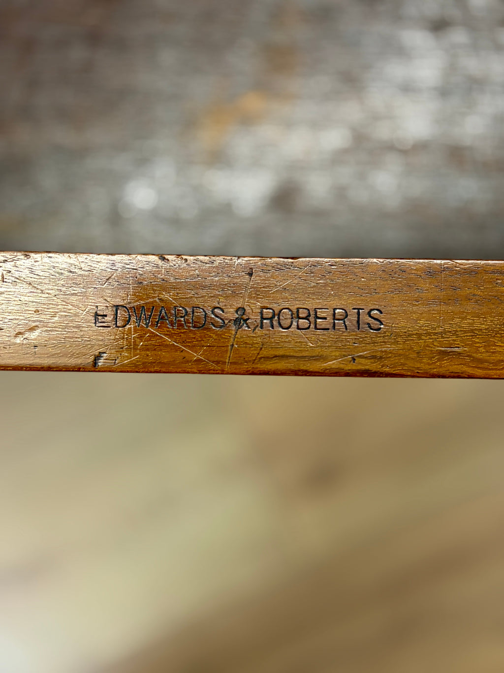 Wooden object with 'Edwards & Roberts' engraving on a blurred background