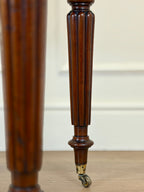 Close-up of a wooden leg with a wheel on a light wood floor.