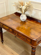 Wooden desk with a vase of dried flowers on a wooden floor.