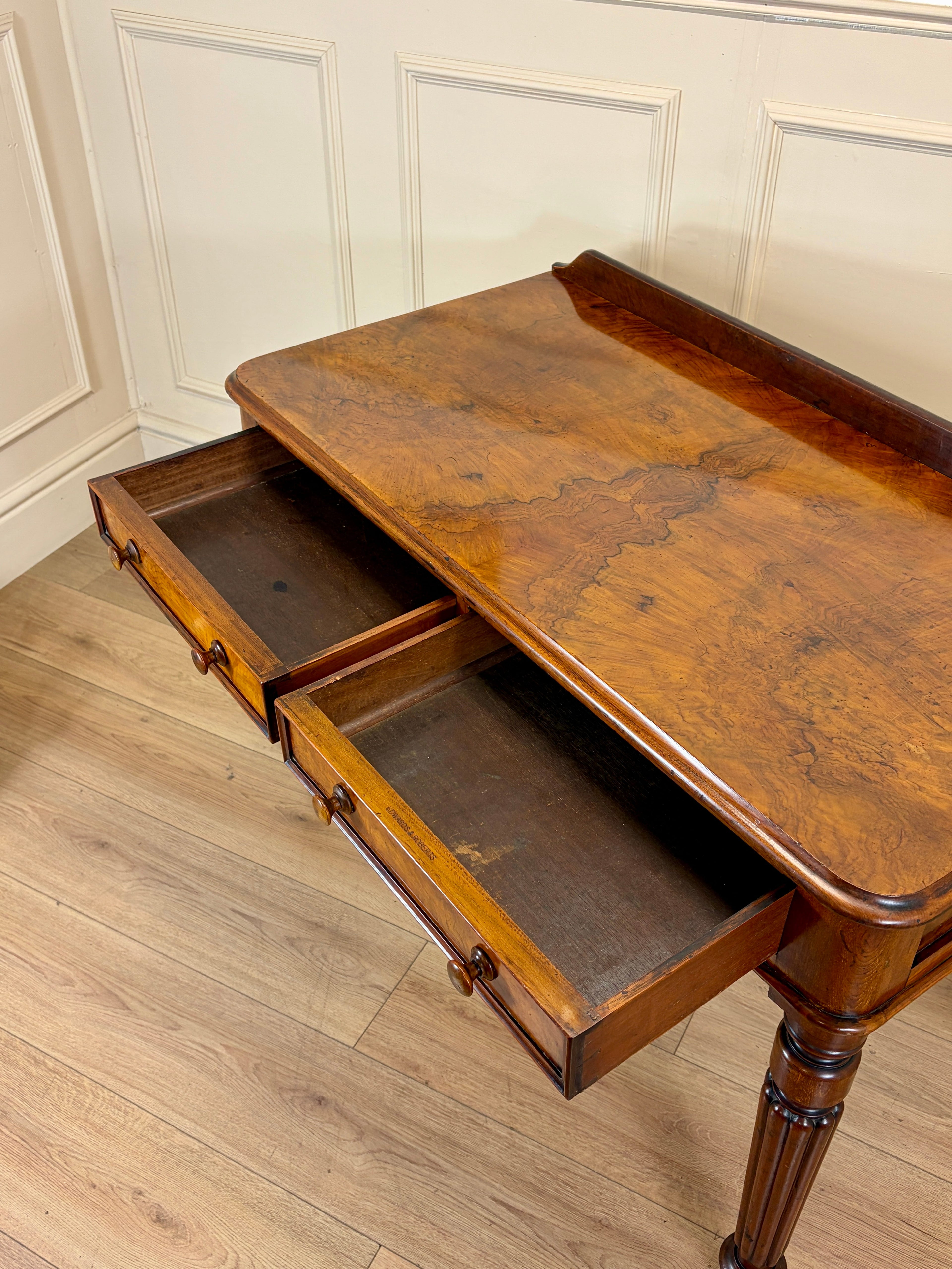 Wooden desk with two drawers open on a wooden floor.