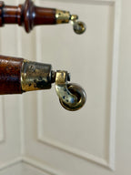 Close-up of a vintage castors with wooden handle and brass accents on a white background