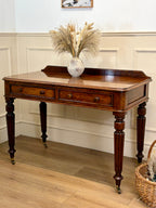 Wooden console table with decorative items in a room with wooden flooring and white walls.
