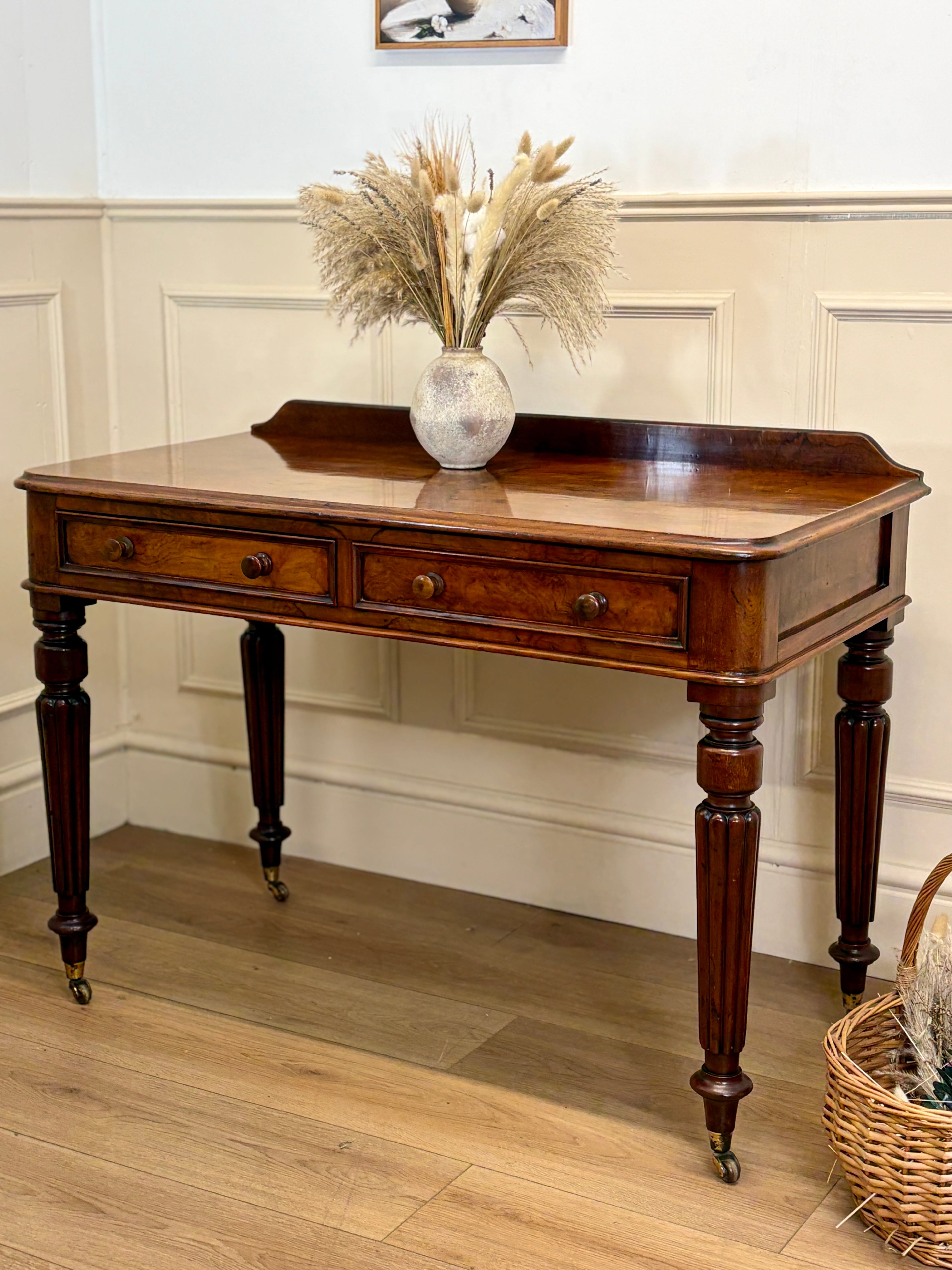 Wooden console table with decorative items in a room with wooden flooring and white walls.