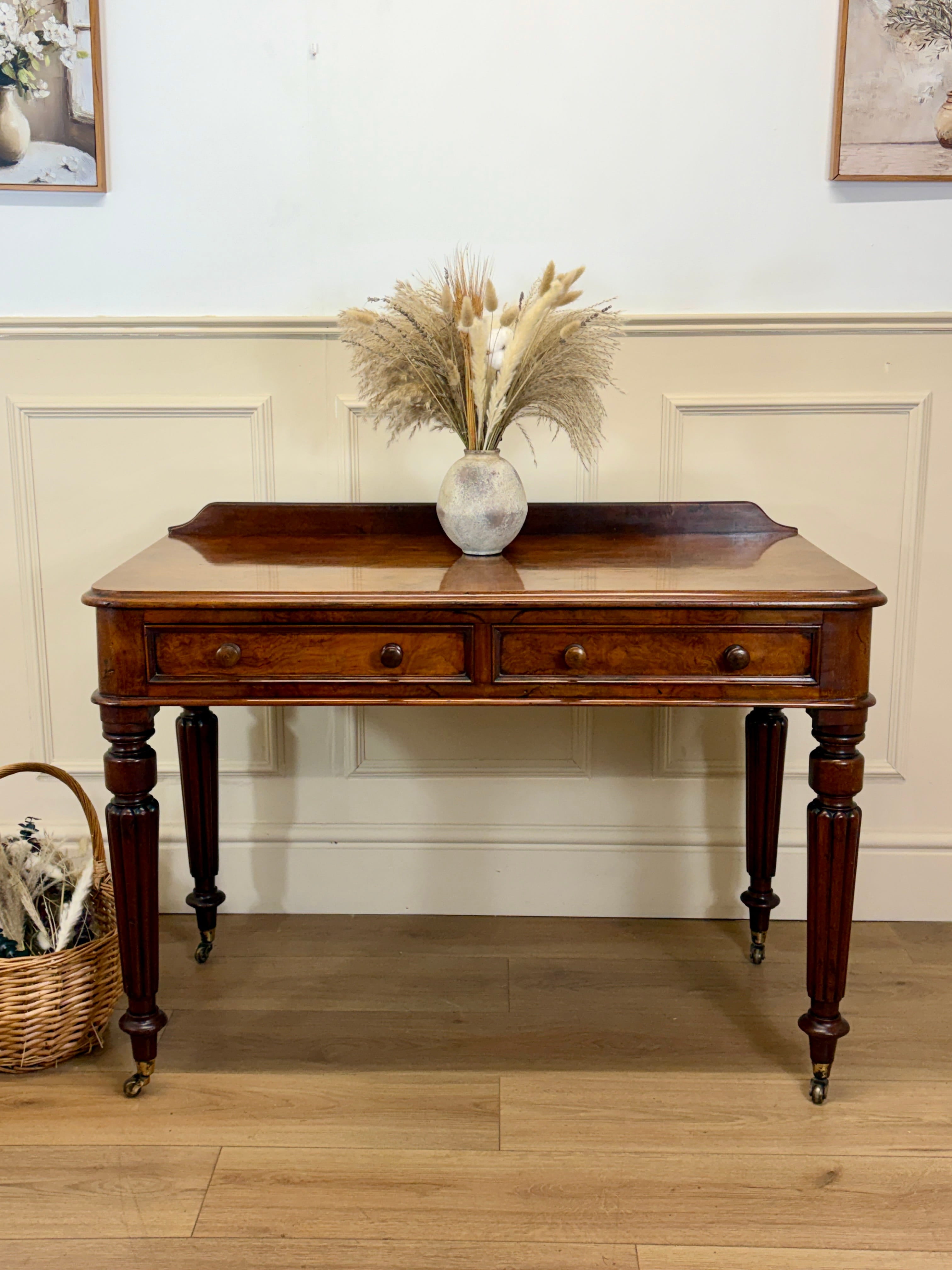 Wooden desk with decorative items in a room with light-colored walls and wooden floor.