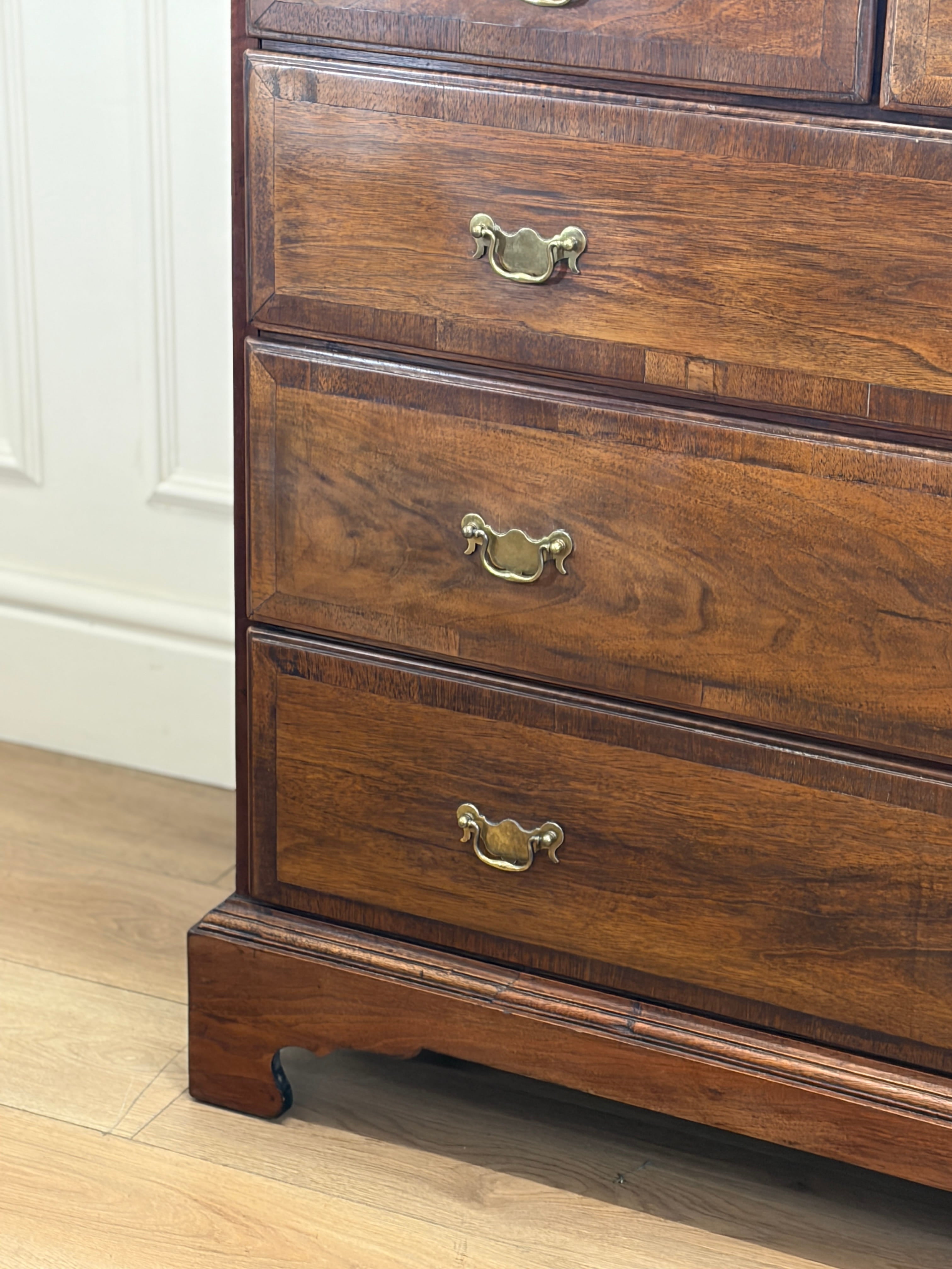 Wooden dresser with brass handles on a wooden floor.