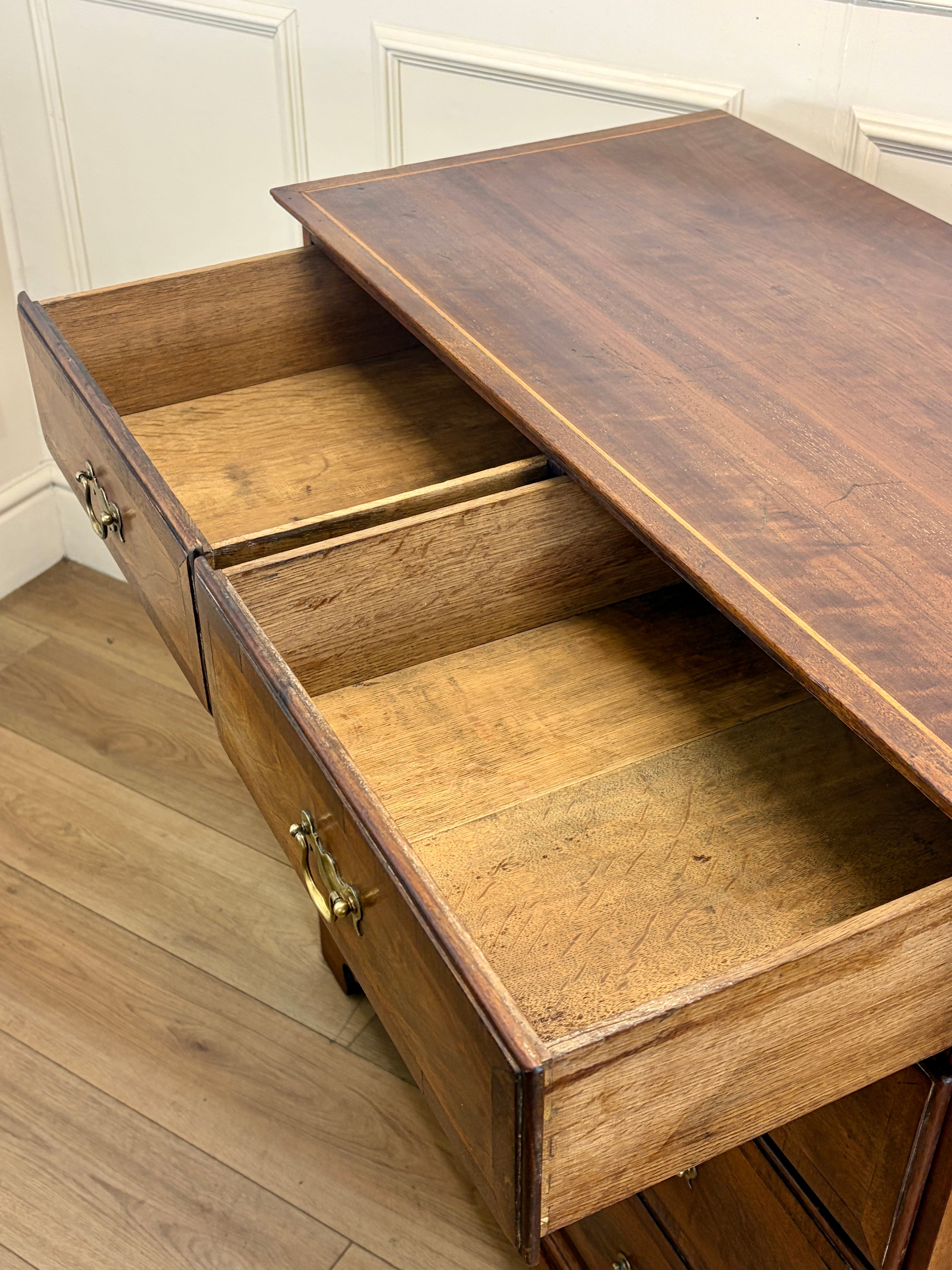 Wooden desk with open drawers in a room with white walls and wooden floor.