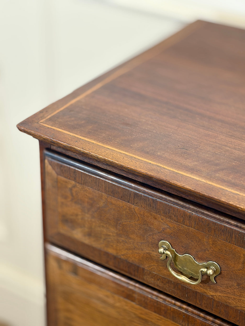 Close-up of a wooden drawer with a brass handle on a white background
