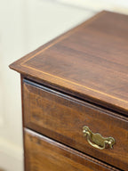 Close-up of a wooden drawer with a brass handle on a white background