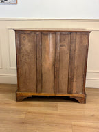 Wooden cabinet with a rustic design on a wooden floor against a white wall.