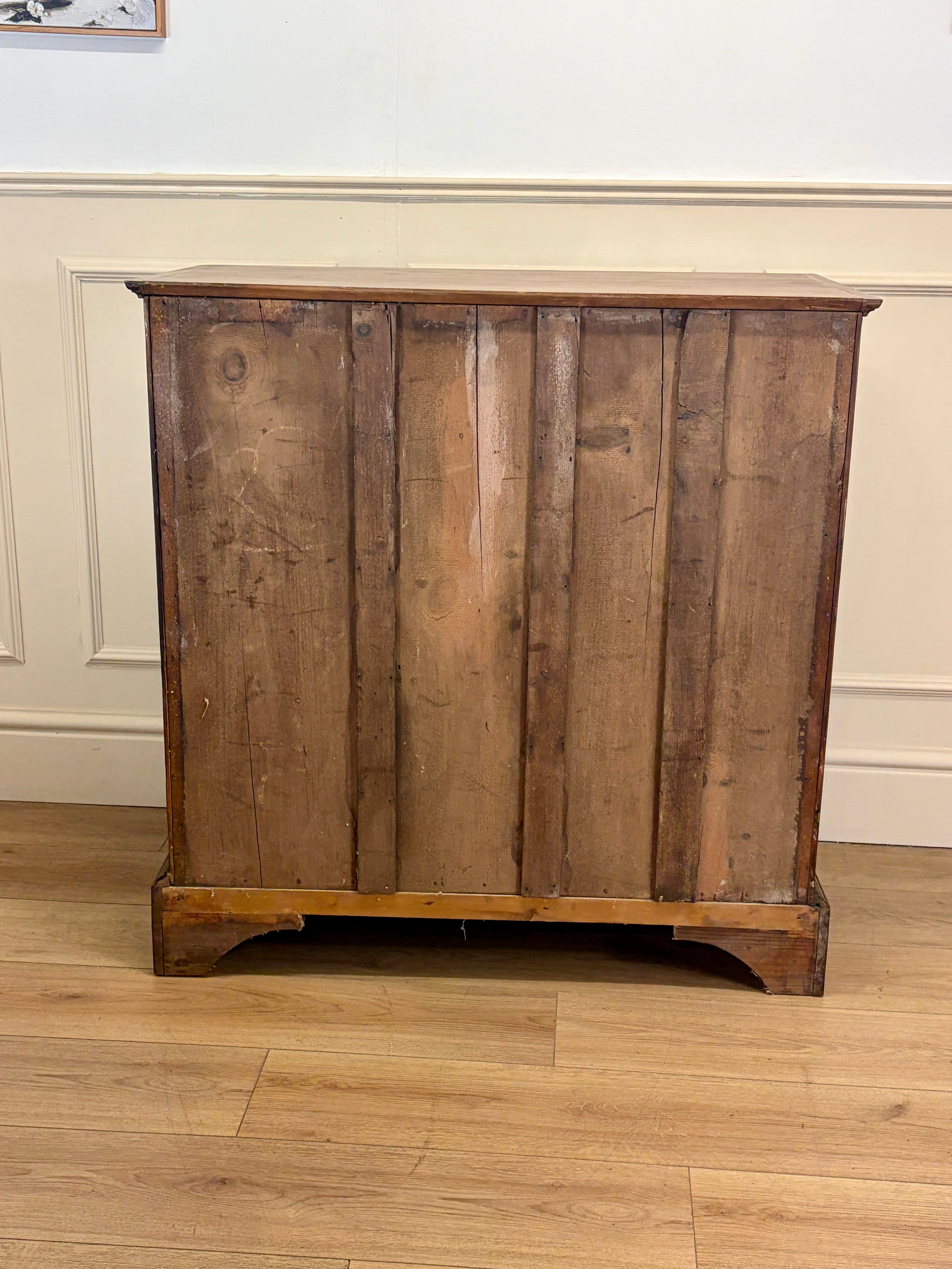Wooden cabinet with a rustic design on a wooden floor against a white wall.