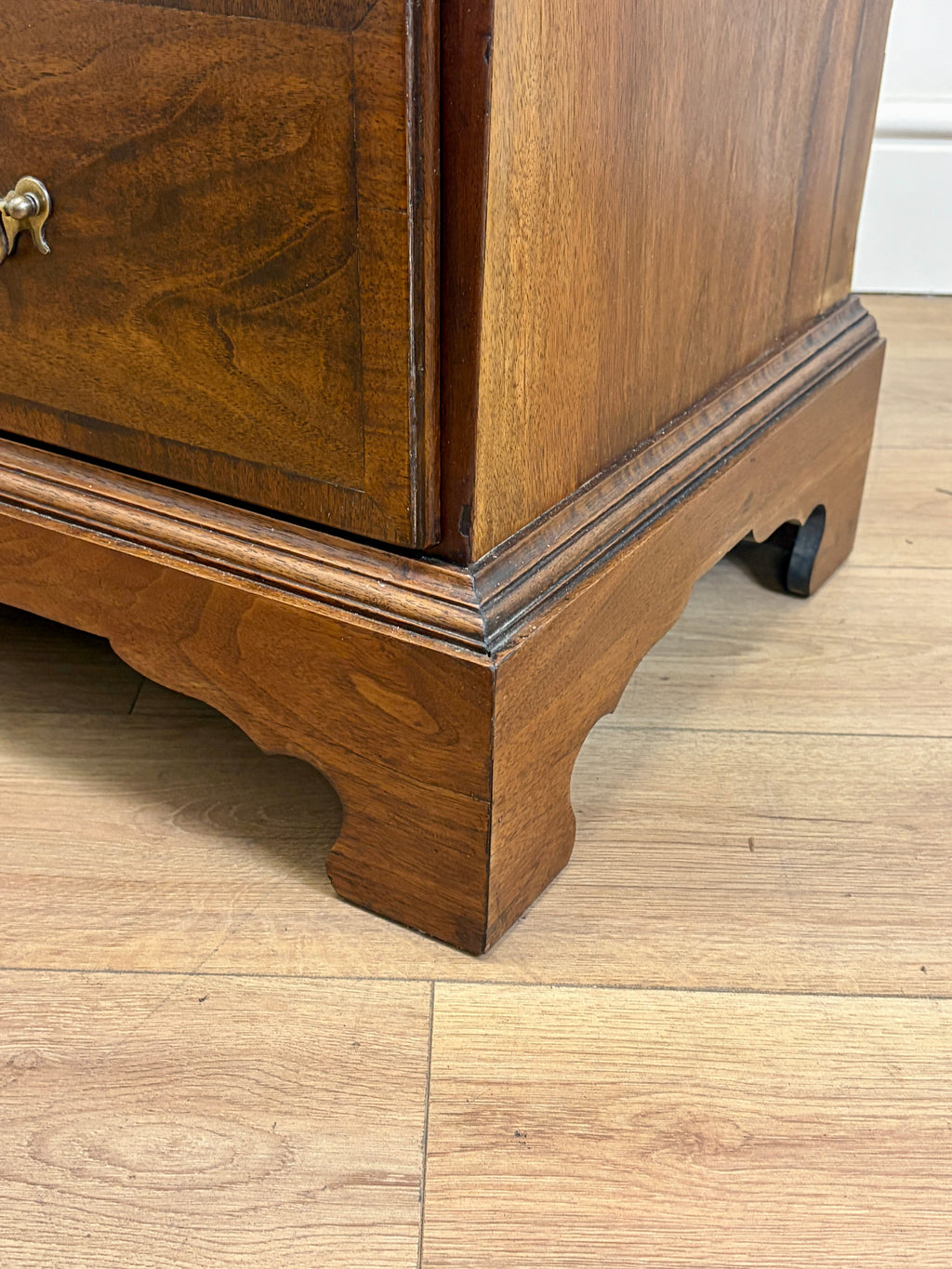 Wooden cabinet with a curved base on a wooden floor