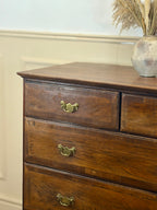 Wooden dresser with three drawers and a decorative vase on top against a light wall.