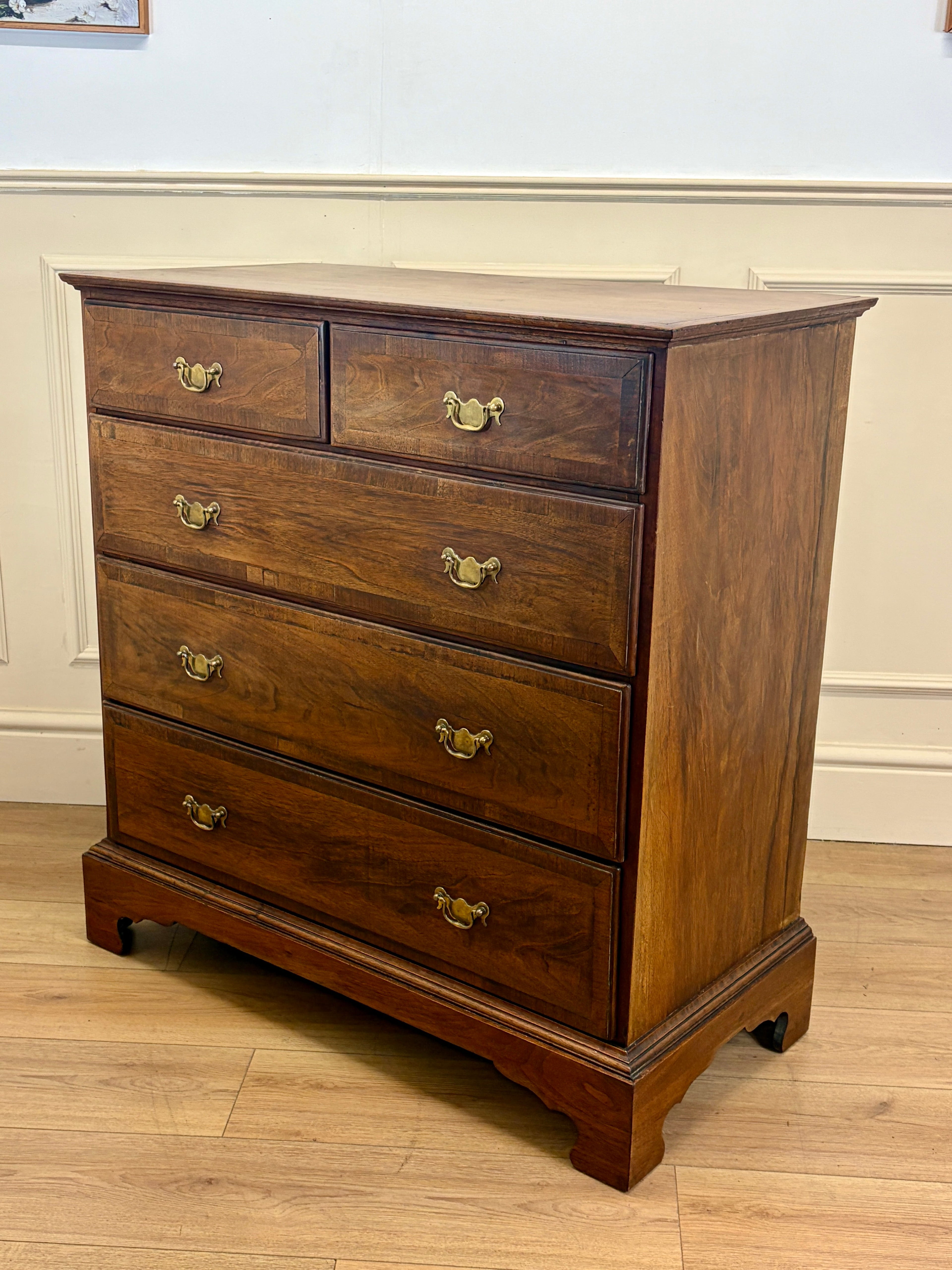 Wooden dresser with four drawers on a wooden floor.