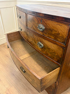 Wooden dresser with curved front and drawers on a wooden floor.