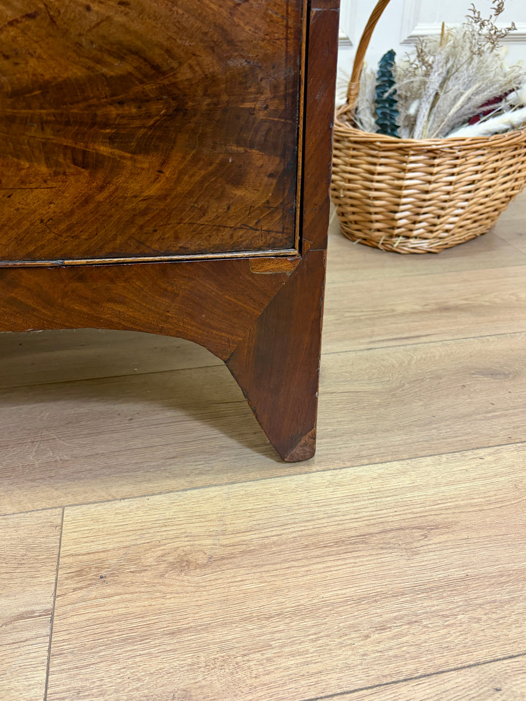 Wooden furniture corner on a wooden floor with a wicker basket in the background.