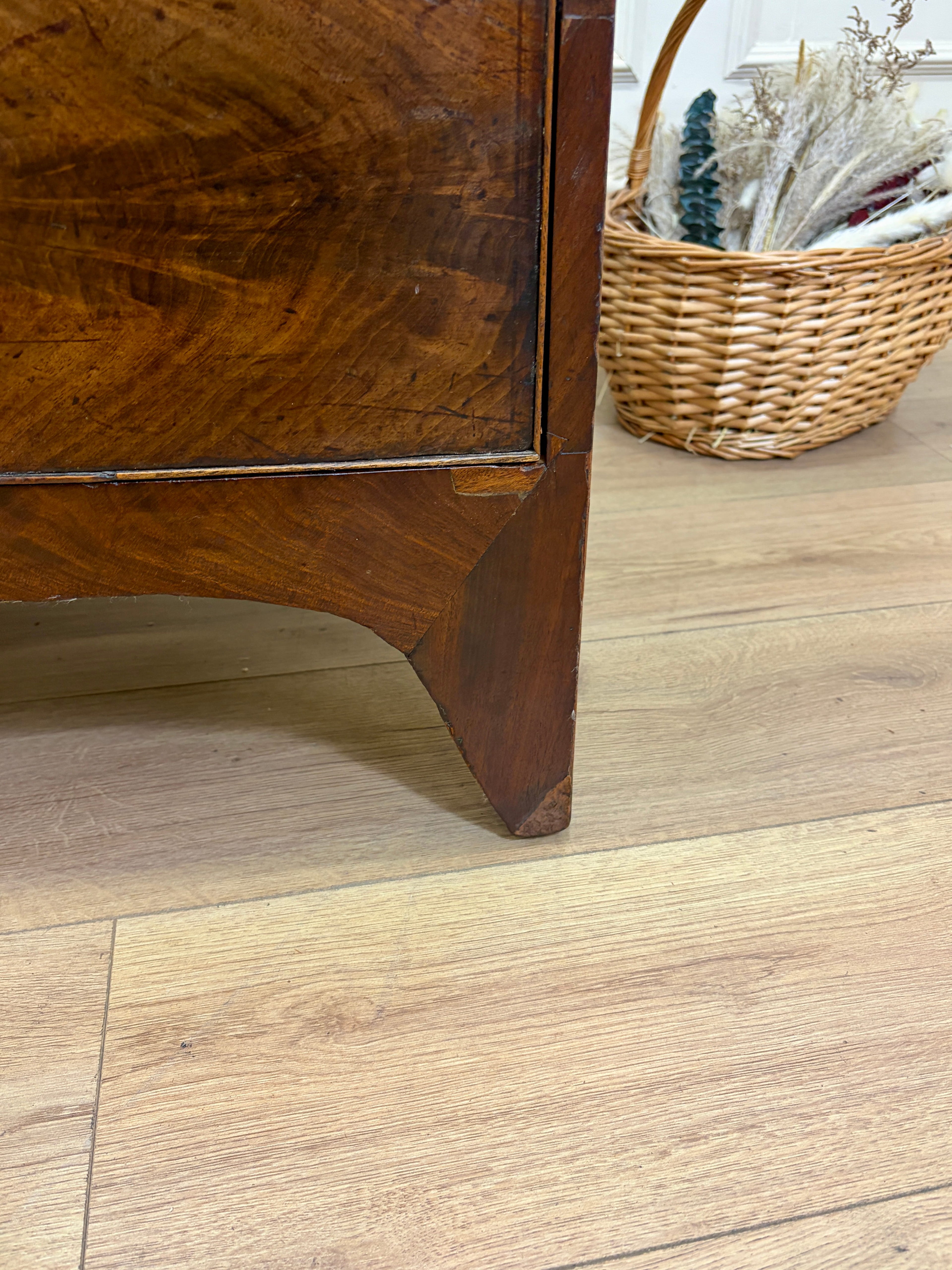 Wooden furniture corner on a wooden floor with a wicker basket in the background.